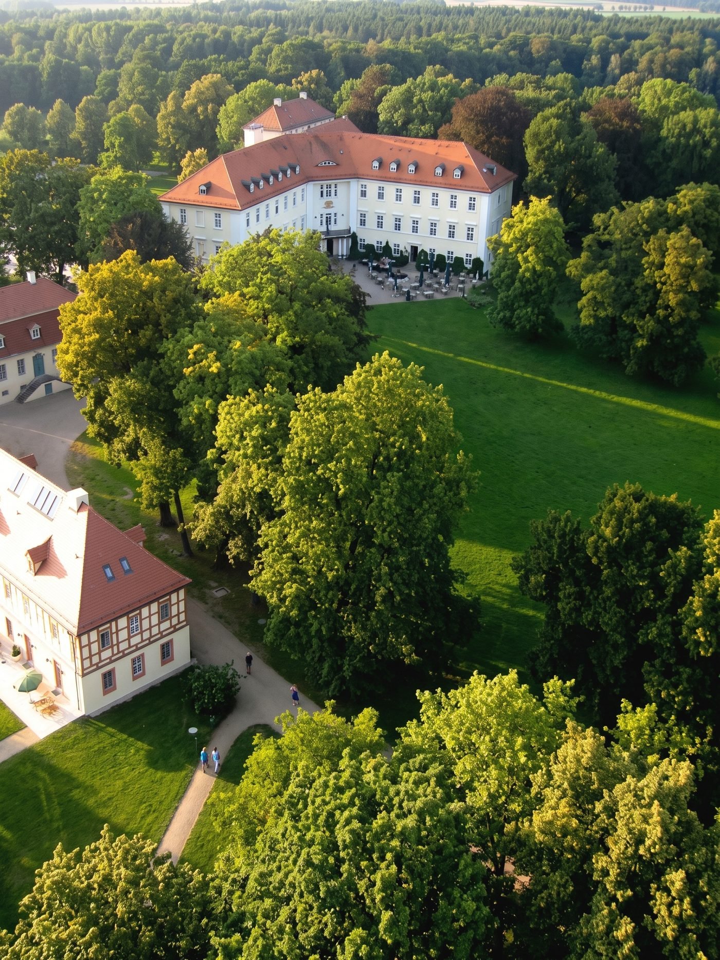 Schloss Lübbenau aus der Luft: weißes Herrenhaus mit rotem Ziegeldach im Schlosspark